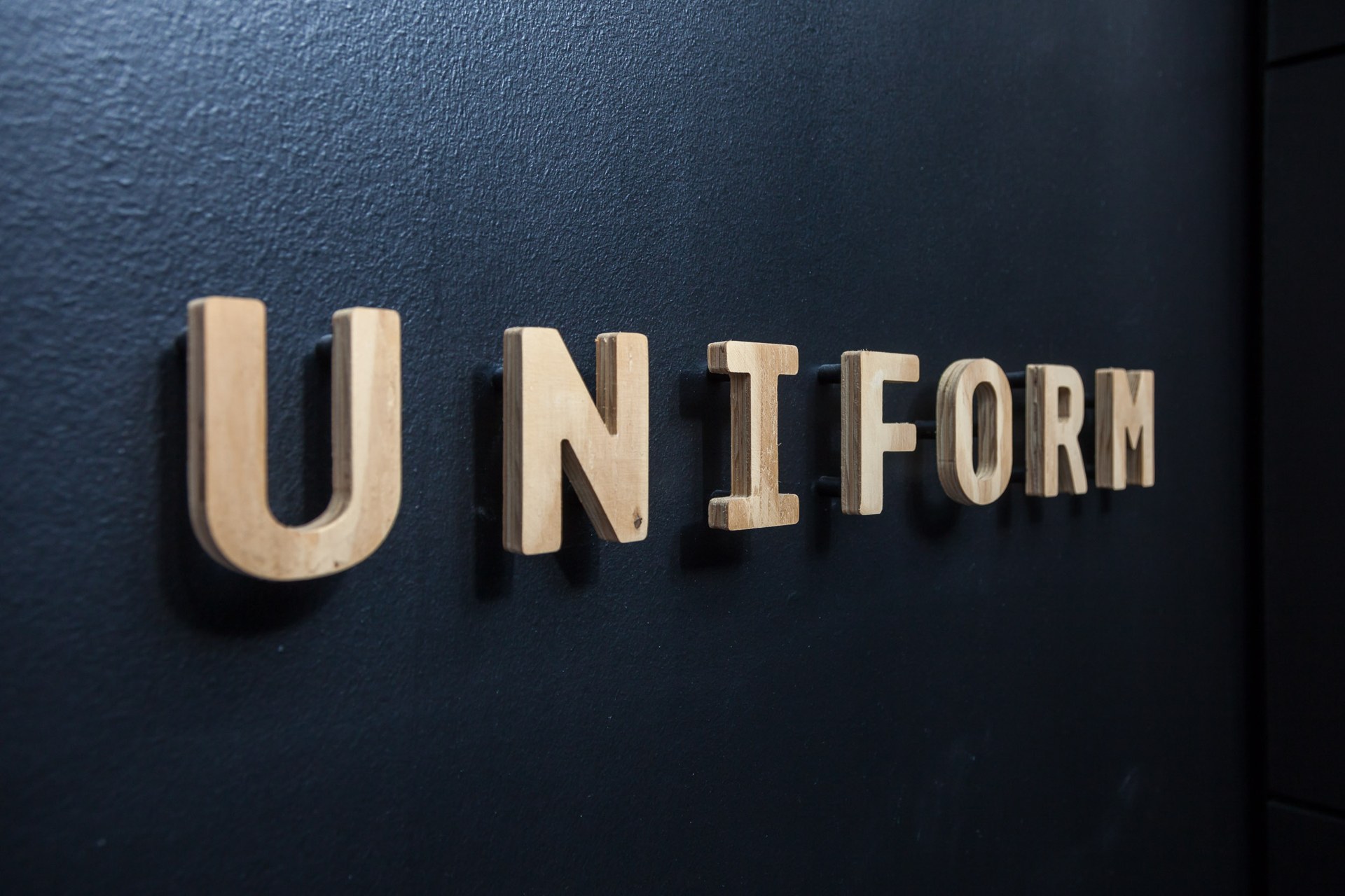Wooden Uniform letters mounted on a dark studio wall