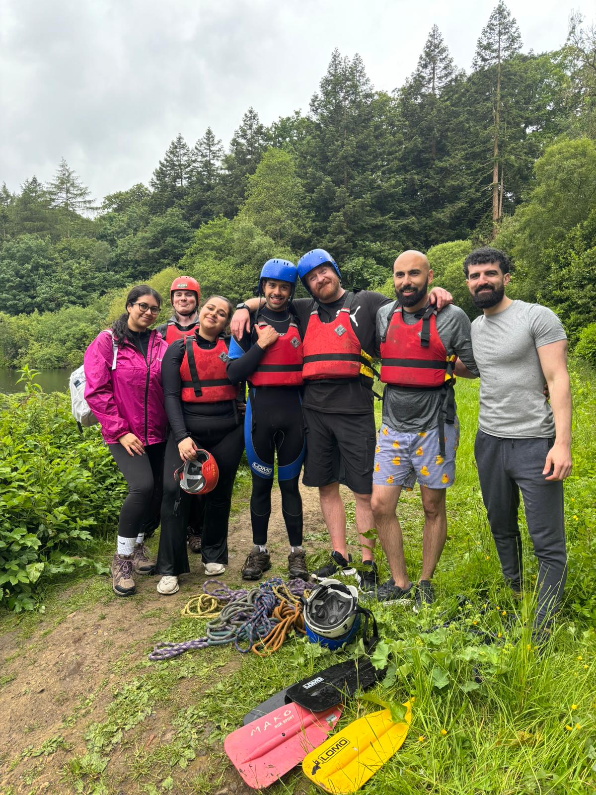 Uniform colleagues wearing helmets and life jackets beside a wooded lake