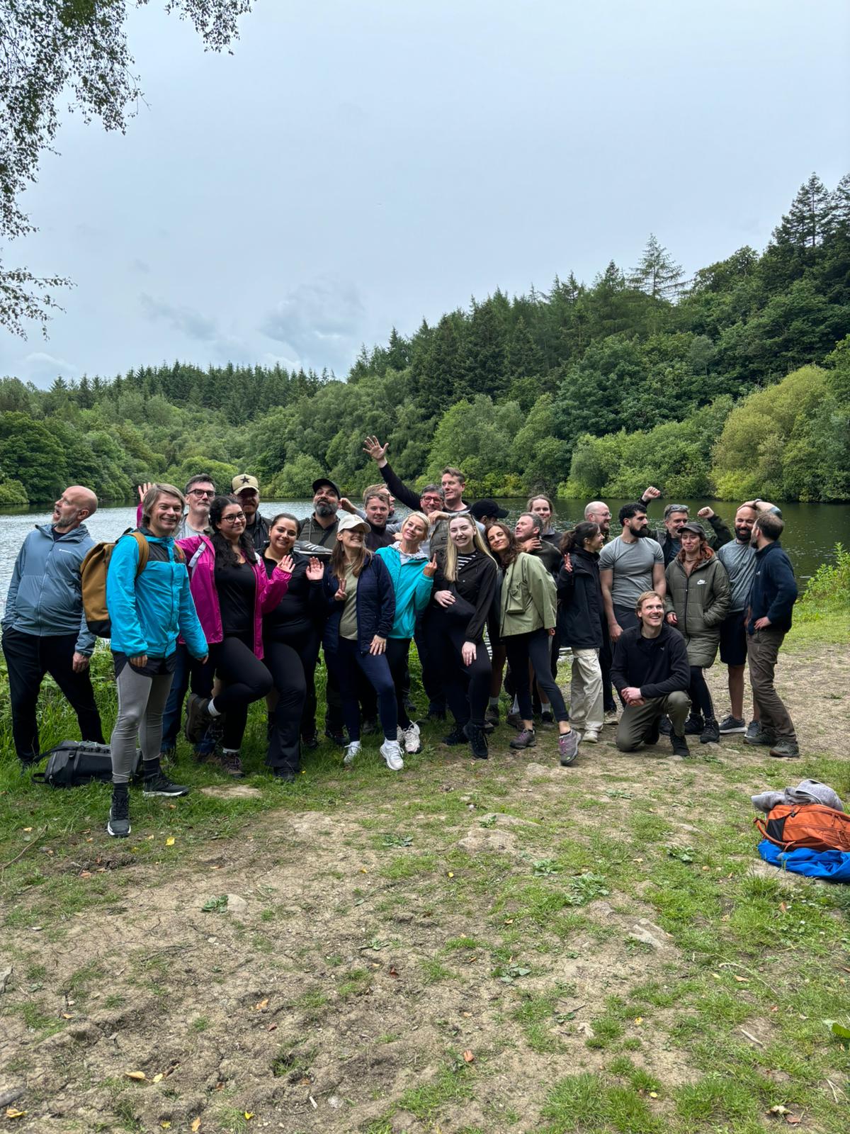 Uniform team together beside a lake surrounded by woodland