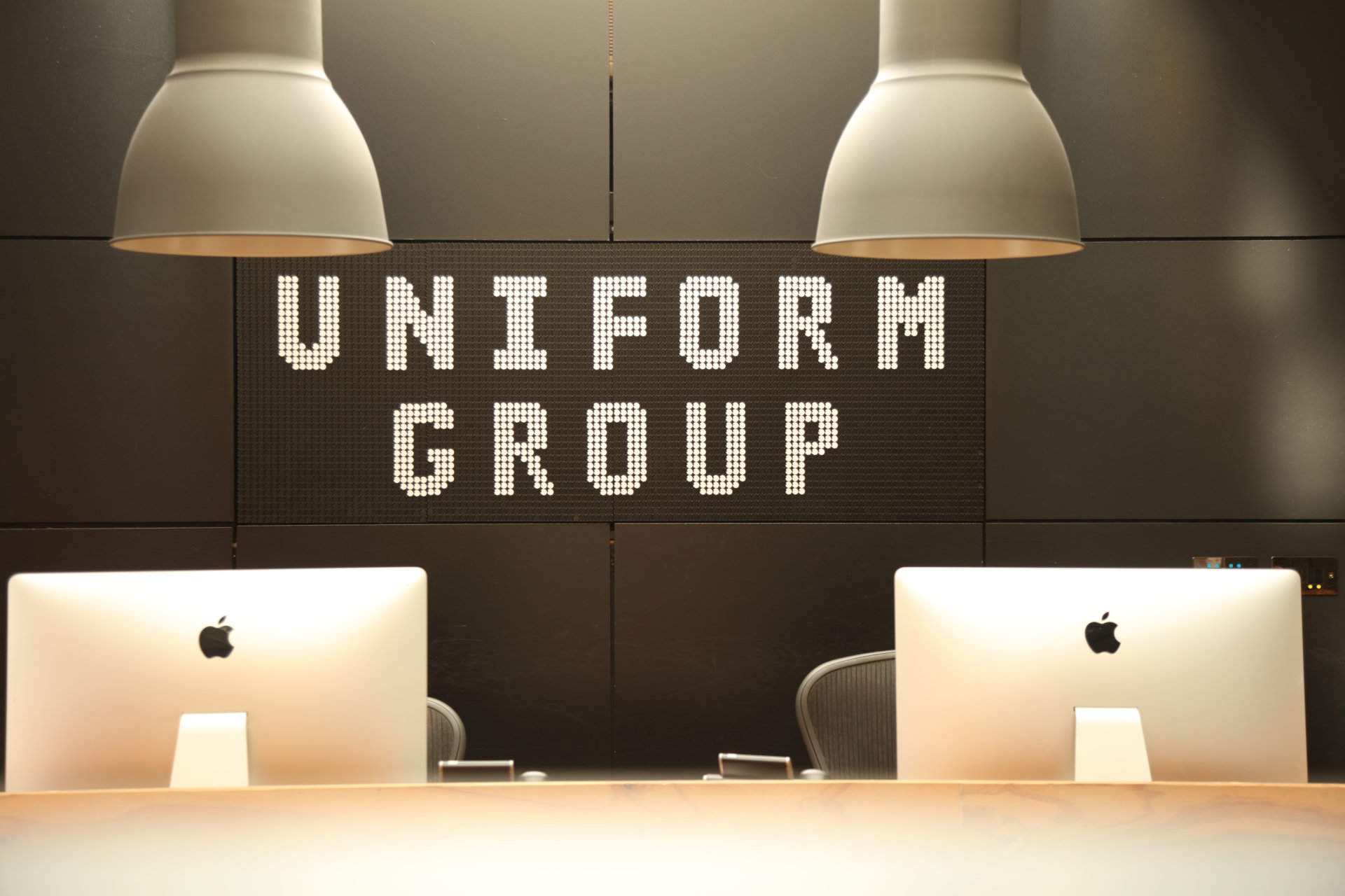 Uniform Group sign above desks and computers in the studio