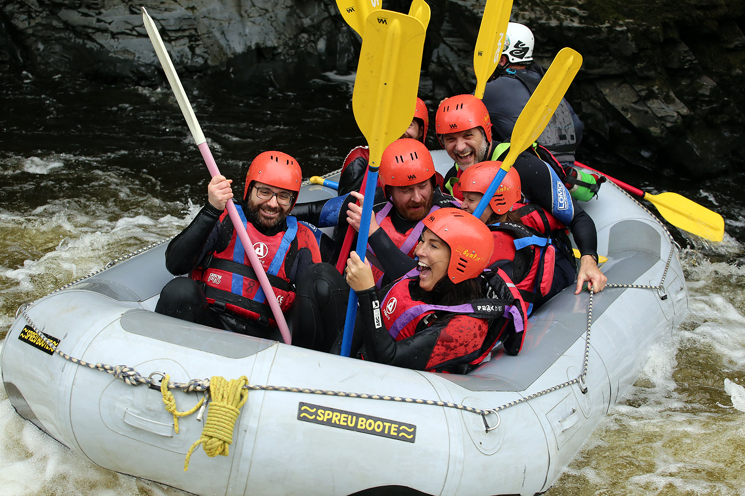 Uniform colleagues paddling together in a white-water raft